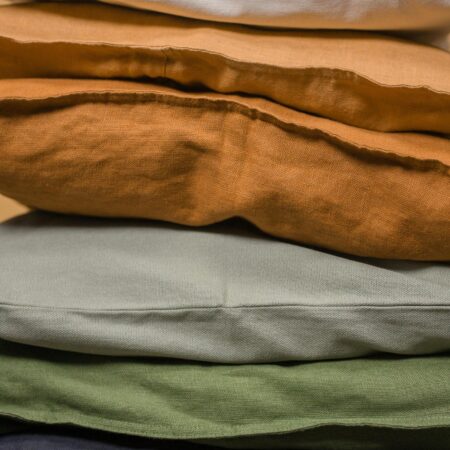 Vertical stack of colorful linen cushions showcasing various textures and tones.